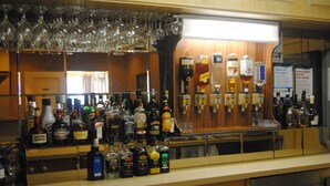 A bar area with various bottles of alcohol, glasses, and a sign indicating no supply under 19.