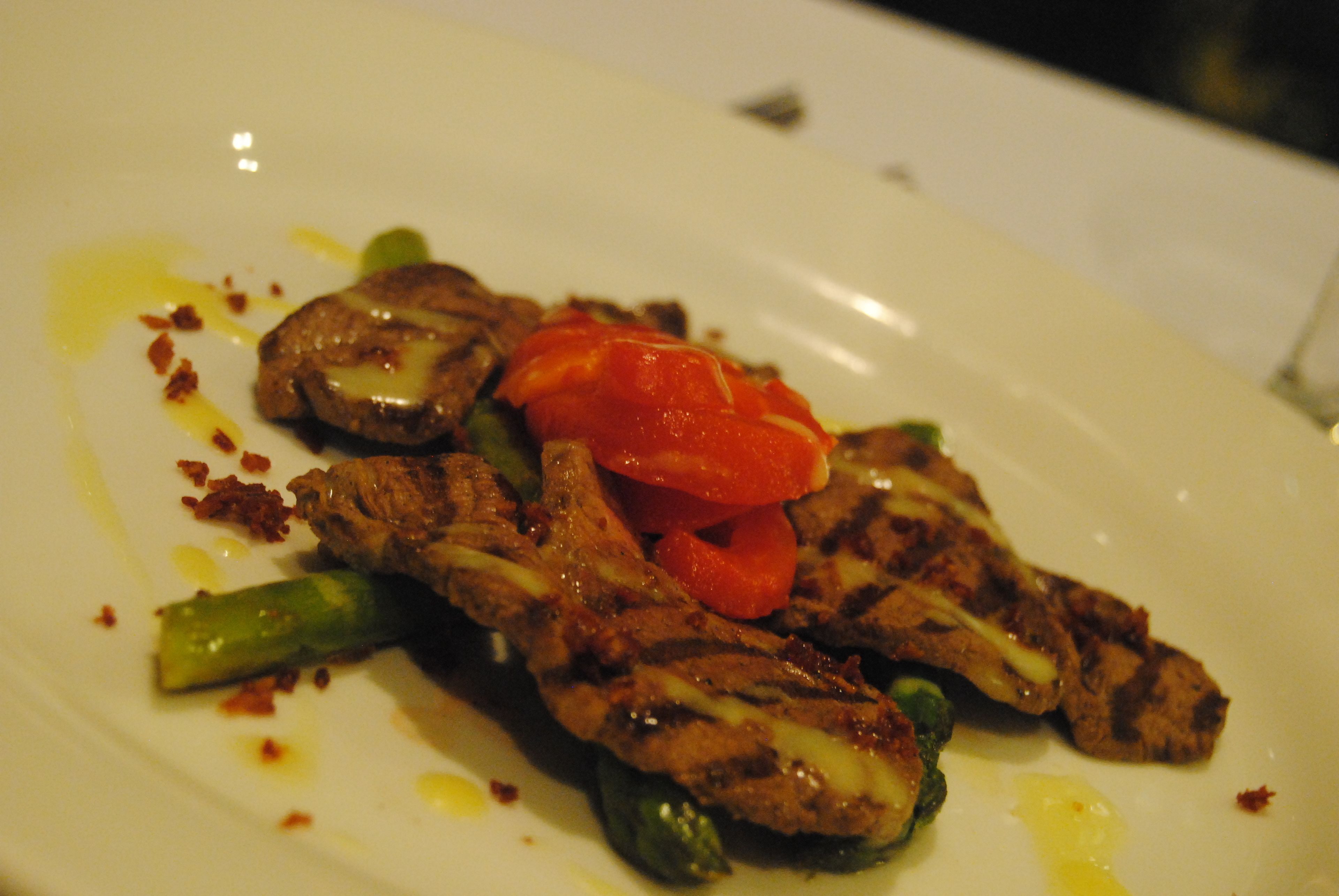 A plate of grilled meat with vegetables and sauce.