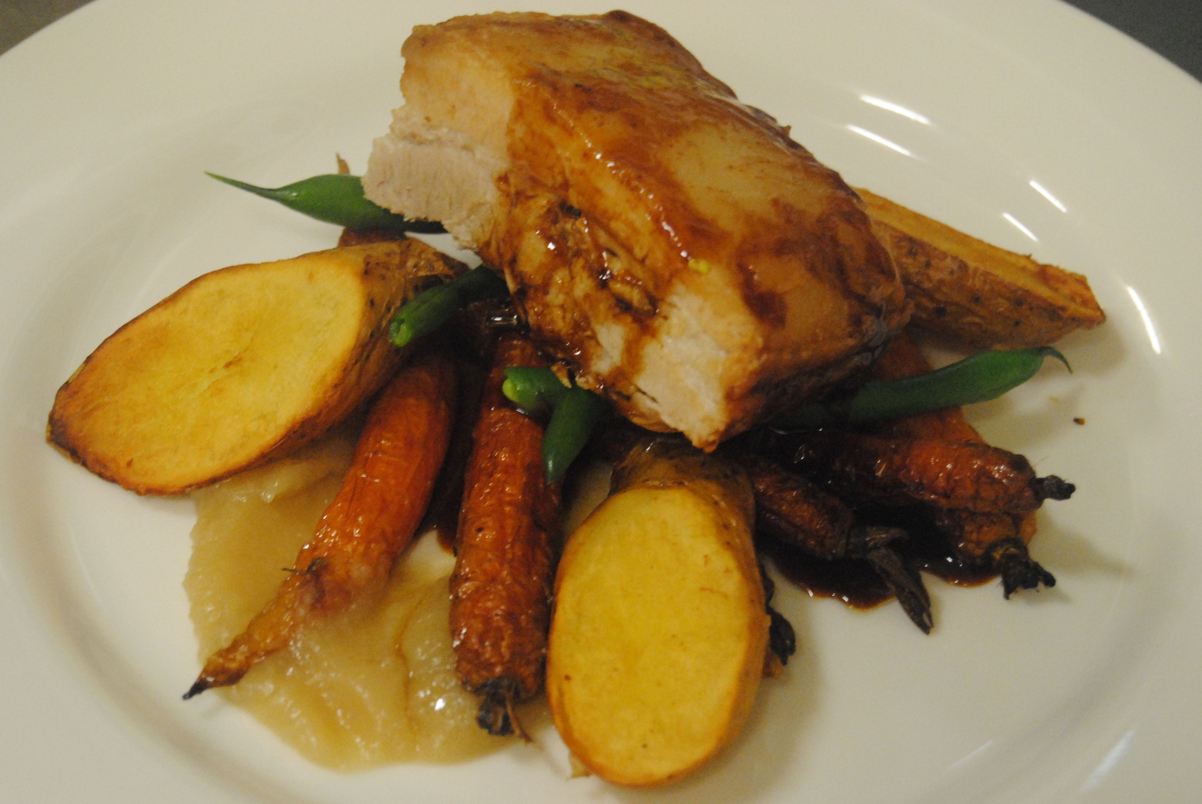 A plate of food with a piece of meat, potatoes, and carrots.