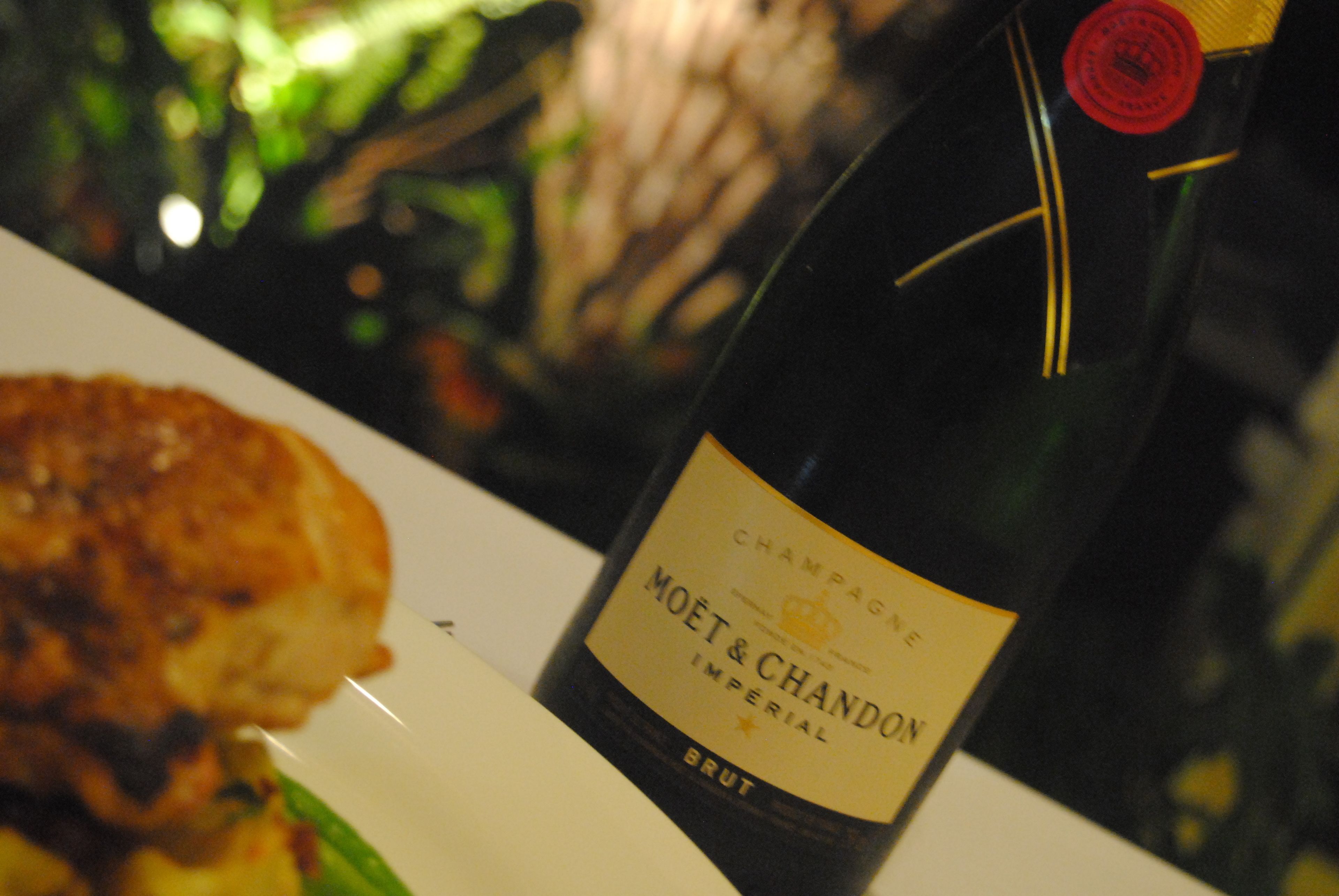 Eine Flasche Moët & Chandon Brut Champagner und ein Teller mit Speisen.
