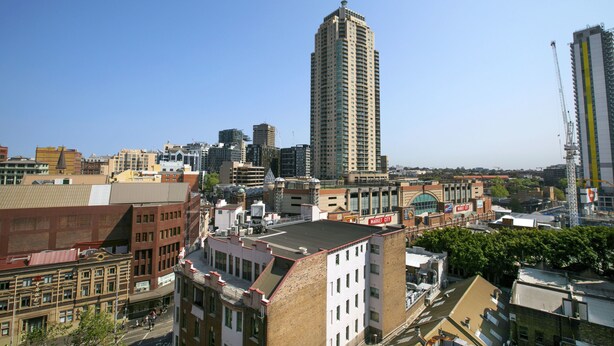 A cityscape with a prominent tall building, a mix of older and modern architecture, and a clear sky. - Mantra Sydney Central (Haymarket)