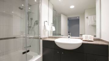 A modern bathroom with a glass-enclosed shower, a white sink, and dark cabinets.