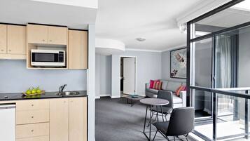 A modern apartment with a kitchen, dining area, and a balcony with a large window.