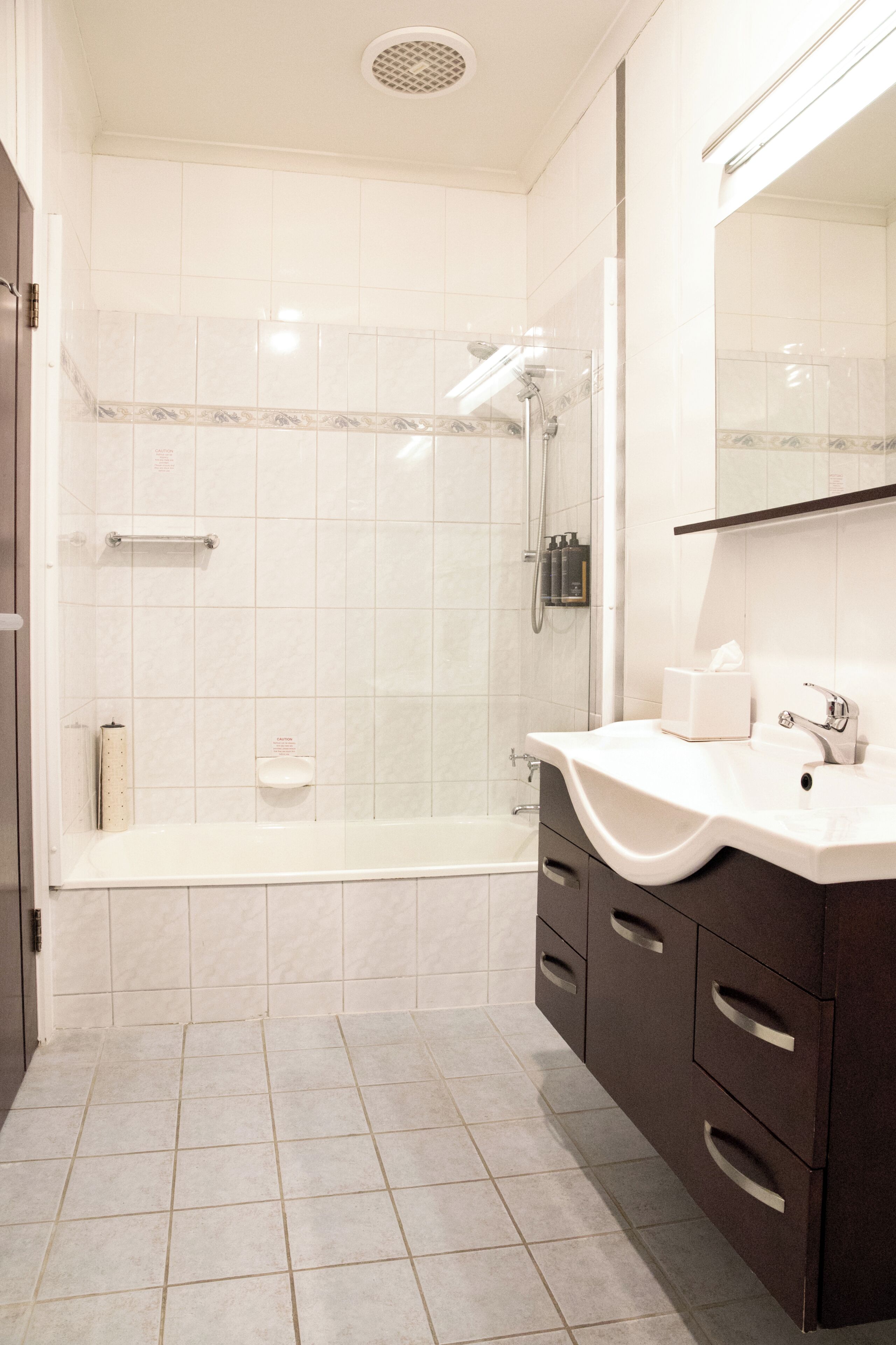 A modern bathroom with a shower, a sink, and a vanity with drawers.