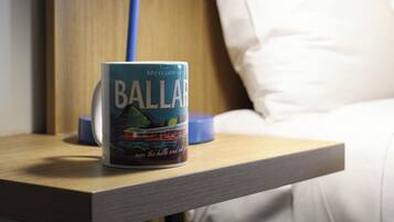 Un libro titulado 'Ballard' sobre una mesita de noche con una lámpara y una cama al fondo.