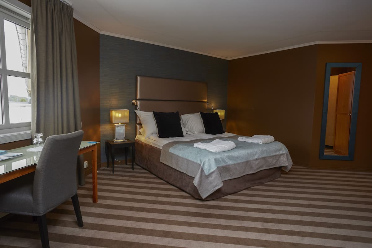Una habitación de hotel con una cama grande, un escritorio y una silla.
