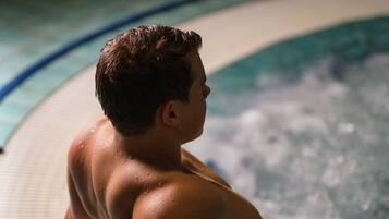 A person standing on a pool deck with a hot tub in the background.