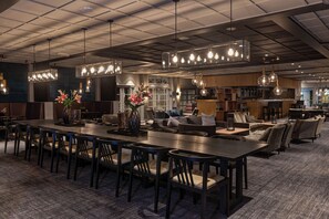 Un restaurant moderne doté d’une longue table conviviale, de plusieurs espaces de détente et de luminaires suspendus.