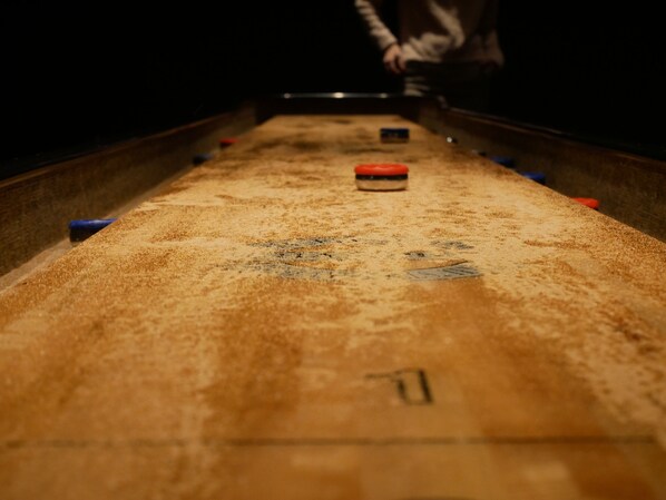 A close-up of a shuffleboard table with numbered scoring areas and pucks.