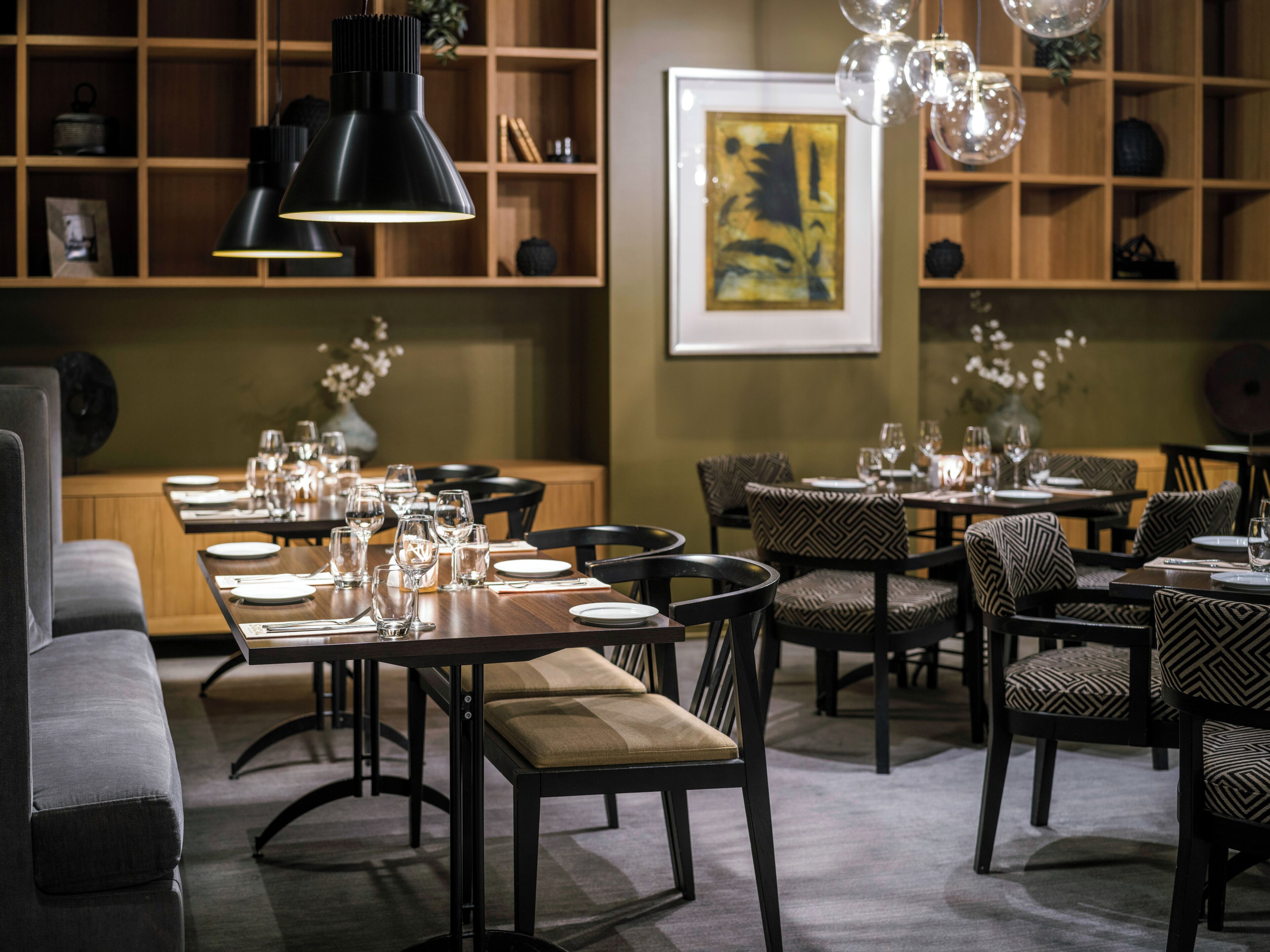 Ein Restaurant mit mehreren Speisetischen, Stühlen und unterschiedlichen Leuchten.