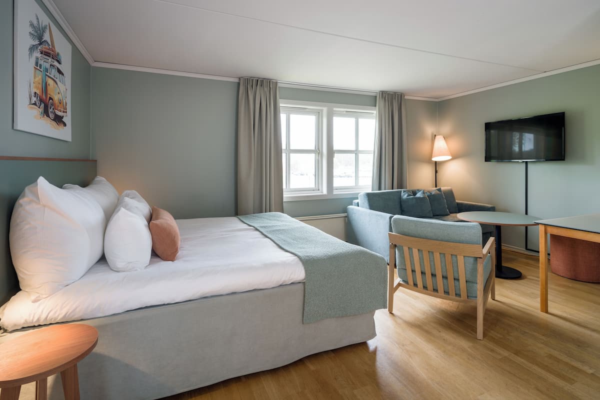 Una habitación de hotel moderna con cama, sofá, escritorio y televisor.