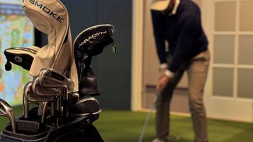 Un bolso de golf con palos y una persona jugando golf al fondo.