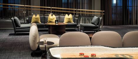 Un espace de détente moderne comprenant des canapés, des fauteuils, une table basse et une table de billard.