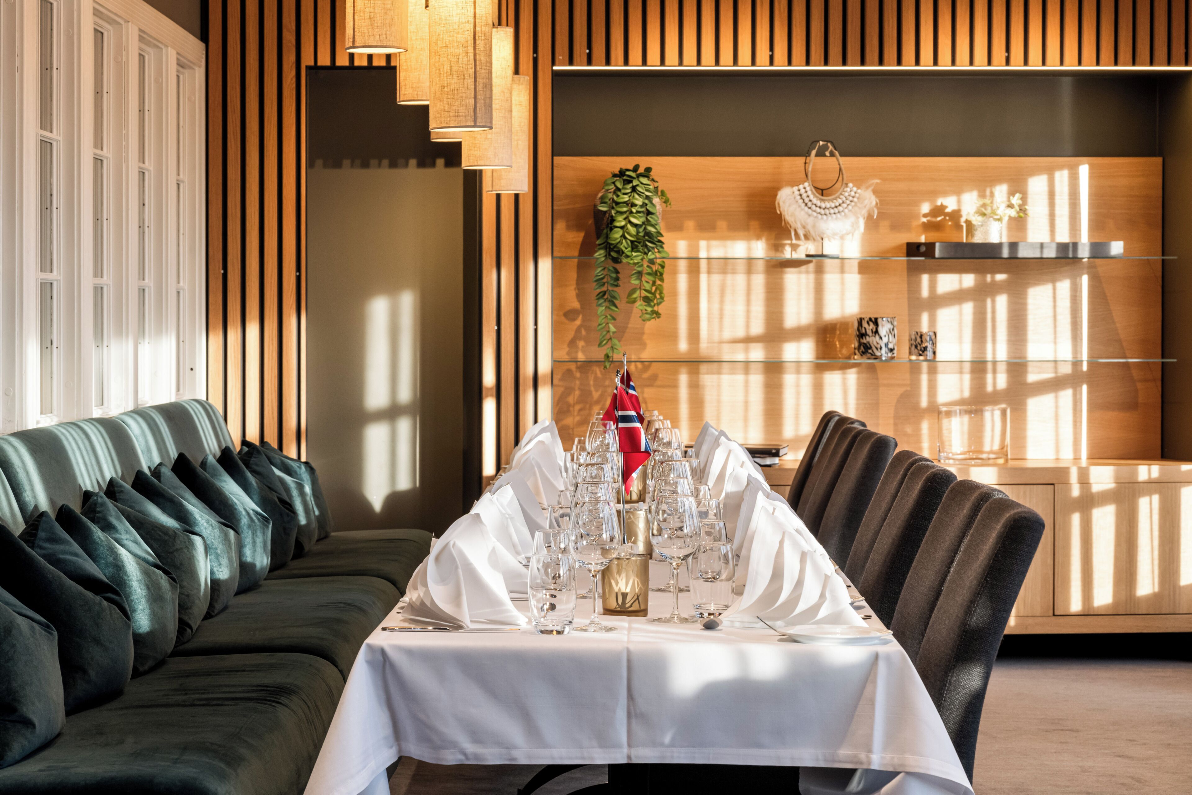 A dining area with a table set for a meal, a sofa, and a decorative plant.