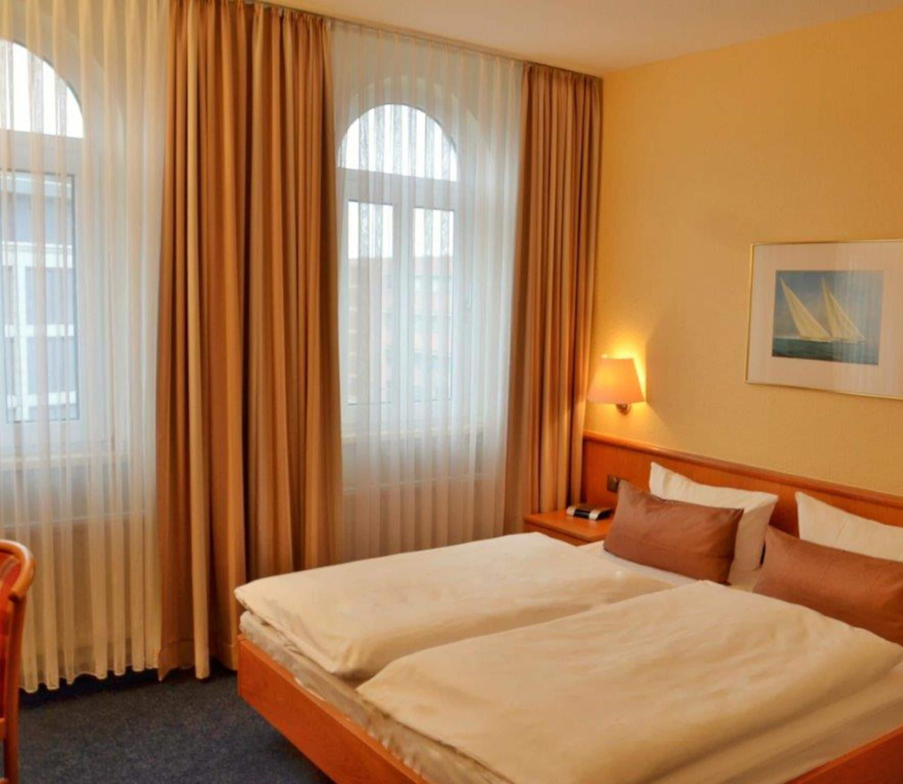 Une chambre d’hôtel avec deux lits, une table de chevet, une lampe et un tableau au mur.