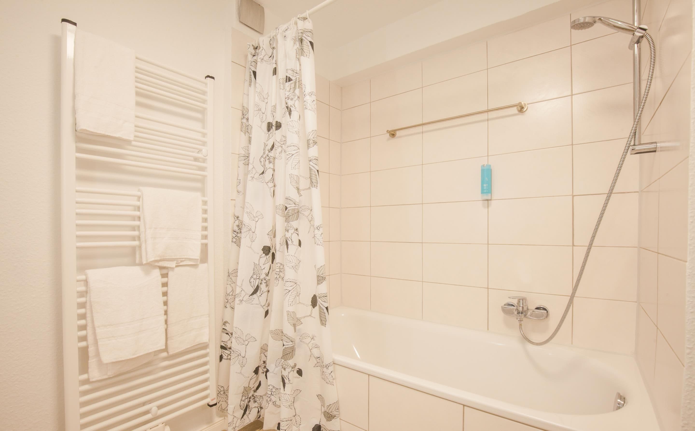 A bathroom with a bathtub, shower, and towel rack.
