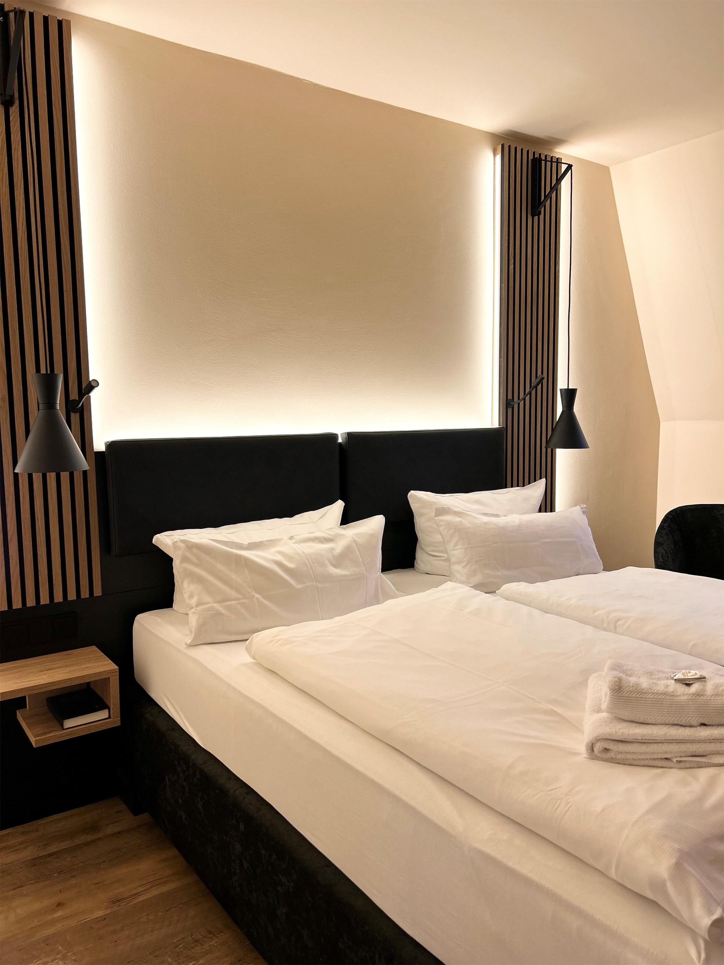 Hotellihuone, jossa on suuri sänky, kaksi yöpöytää ja pääty, jossa on pystysuoria juovia.