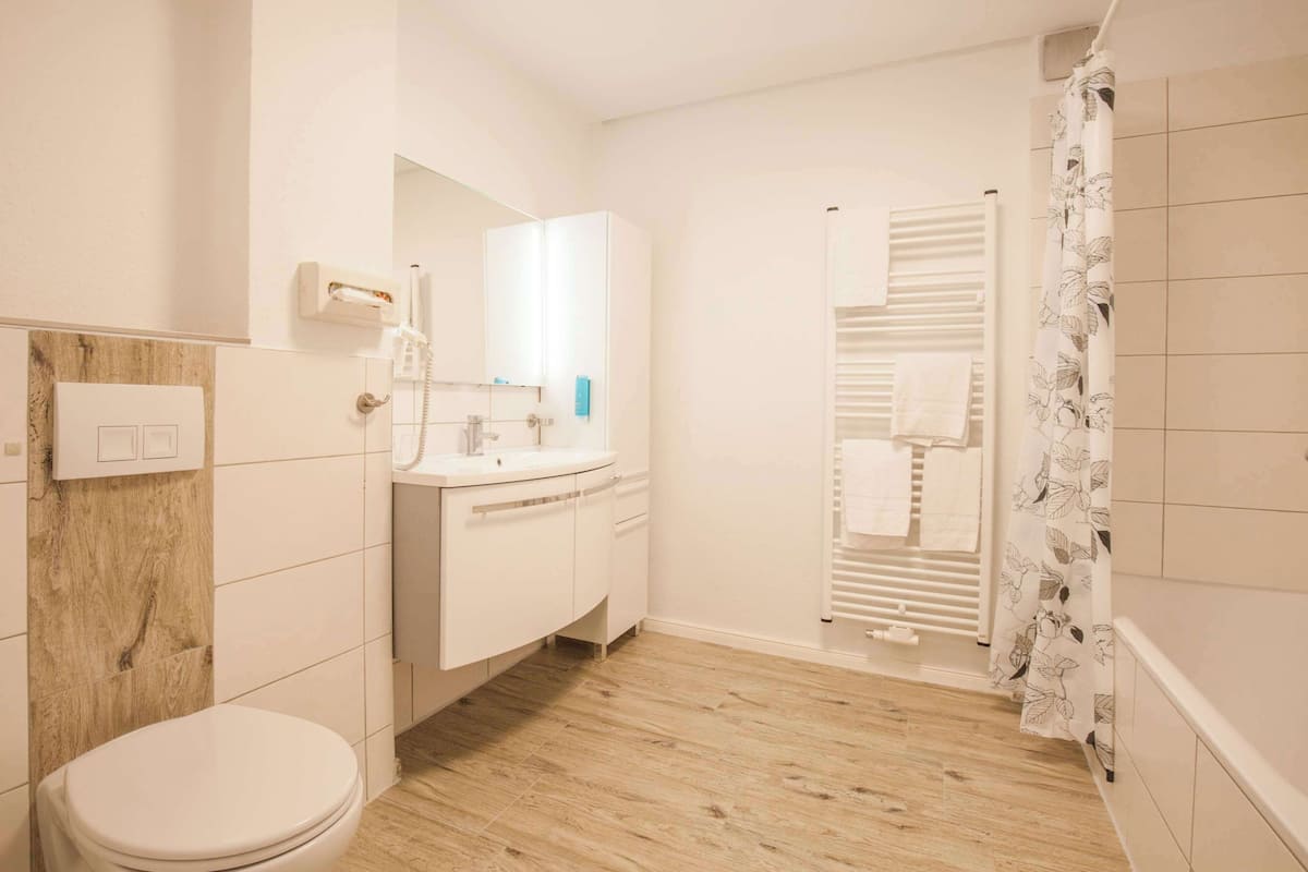 Un baño moderno con inodoro, lavabo, espejo y ducha.