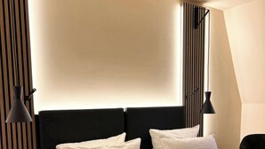 Una habitación de hotel moderna con una cama grande, dos mesitas de noche y un cabecero con líneas verticales.