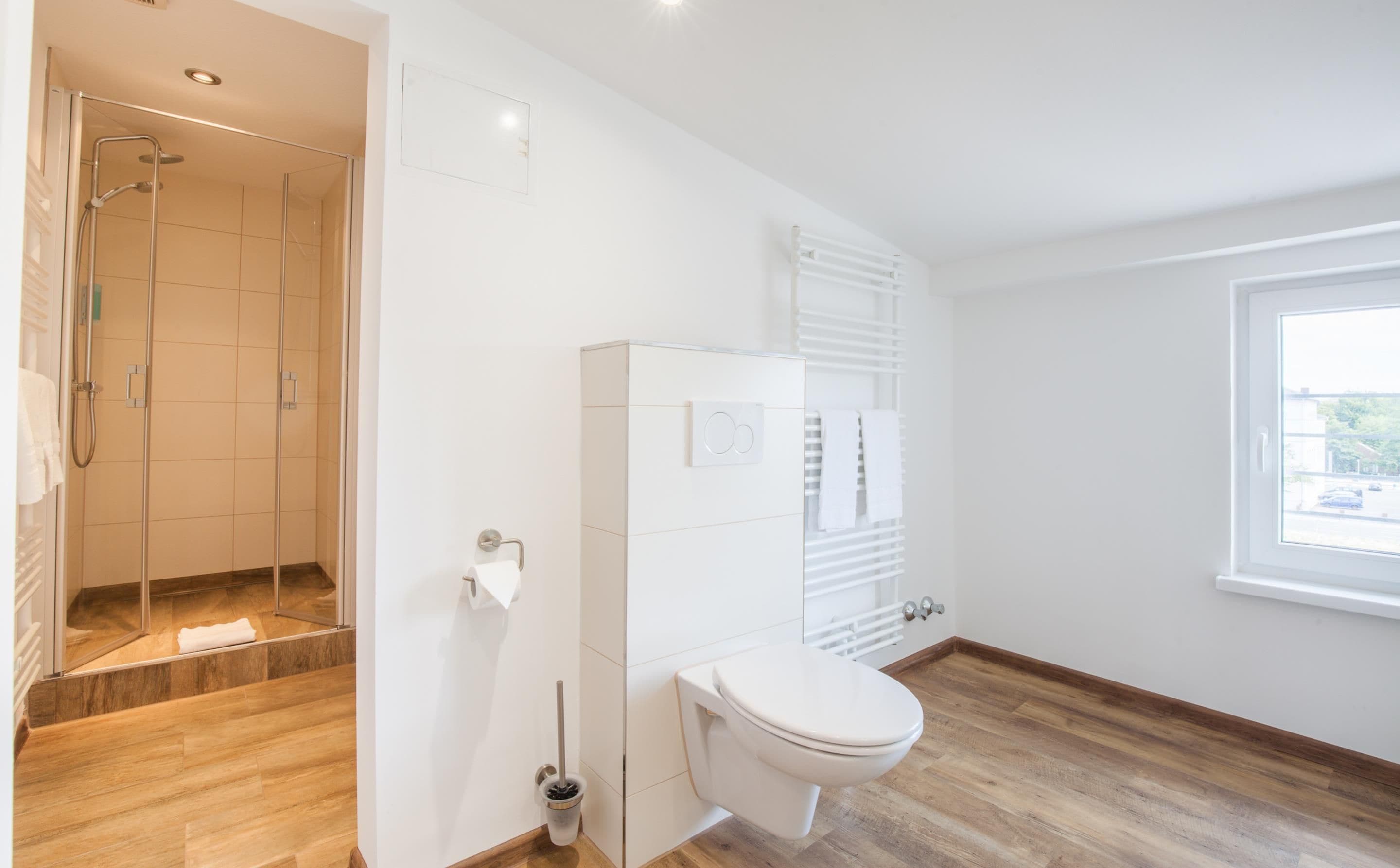 Ein modernes Badezimmer mit Dusche, Toilette und einem Fenster.