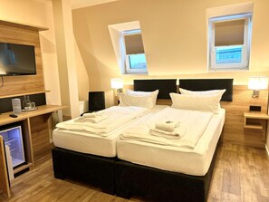 Une chambre d’hôtel équipée d’un lit, de tables de chevet, d’une télévision et d’un bureau avec un ordinateur et des lunettes.