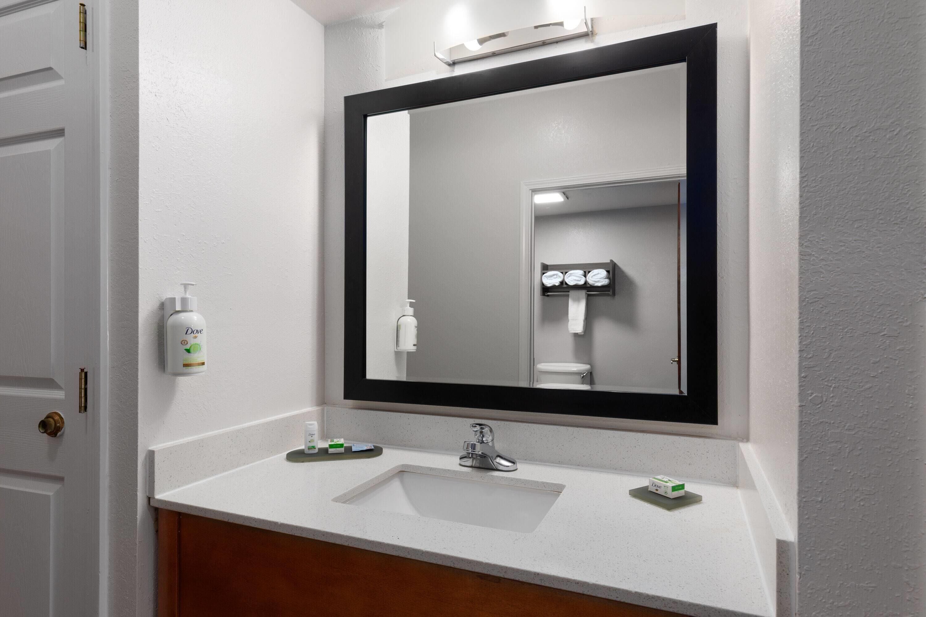 A bathroom with a white sink, a large mirror, and a door.