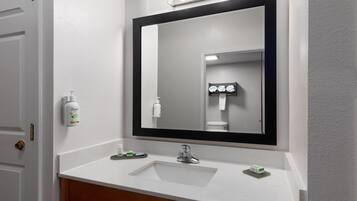 A bathroom with a white sink, a large mirror, and a door.