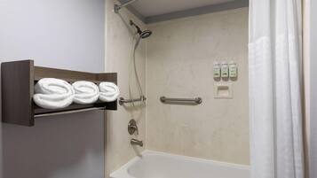 A bathroom with a bathtub, a shower, and a shelf with towels.