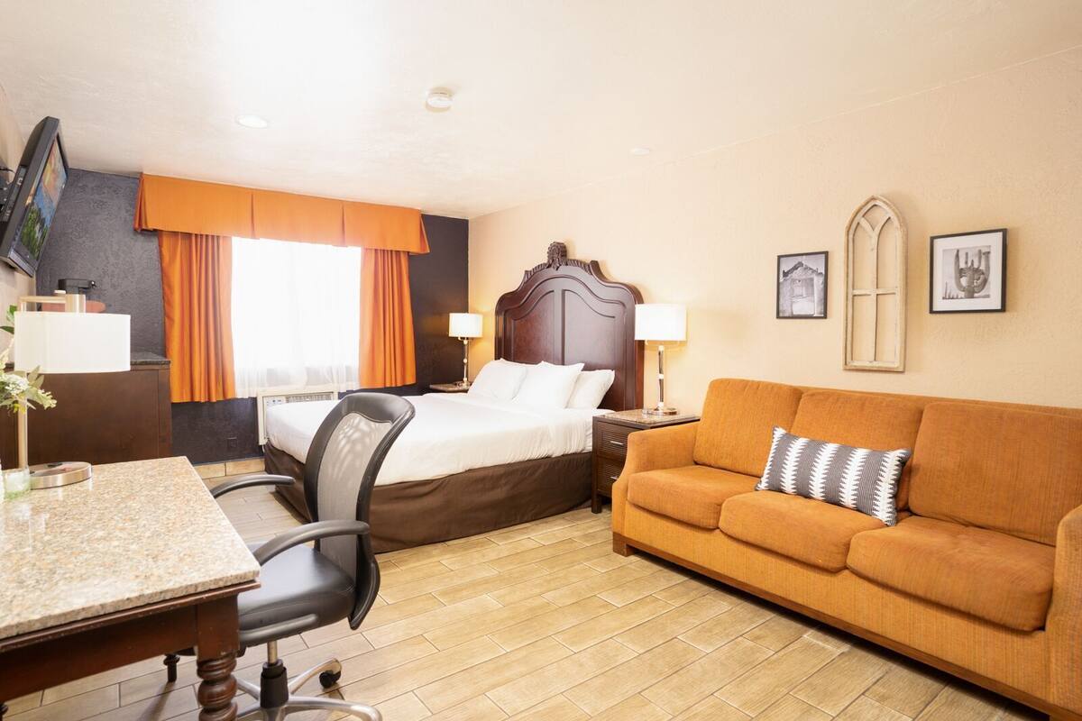 A hotel room with a bed, a sofa, a desk, and a chair.