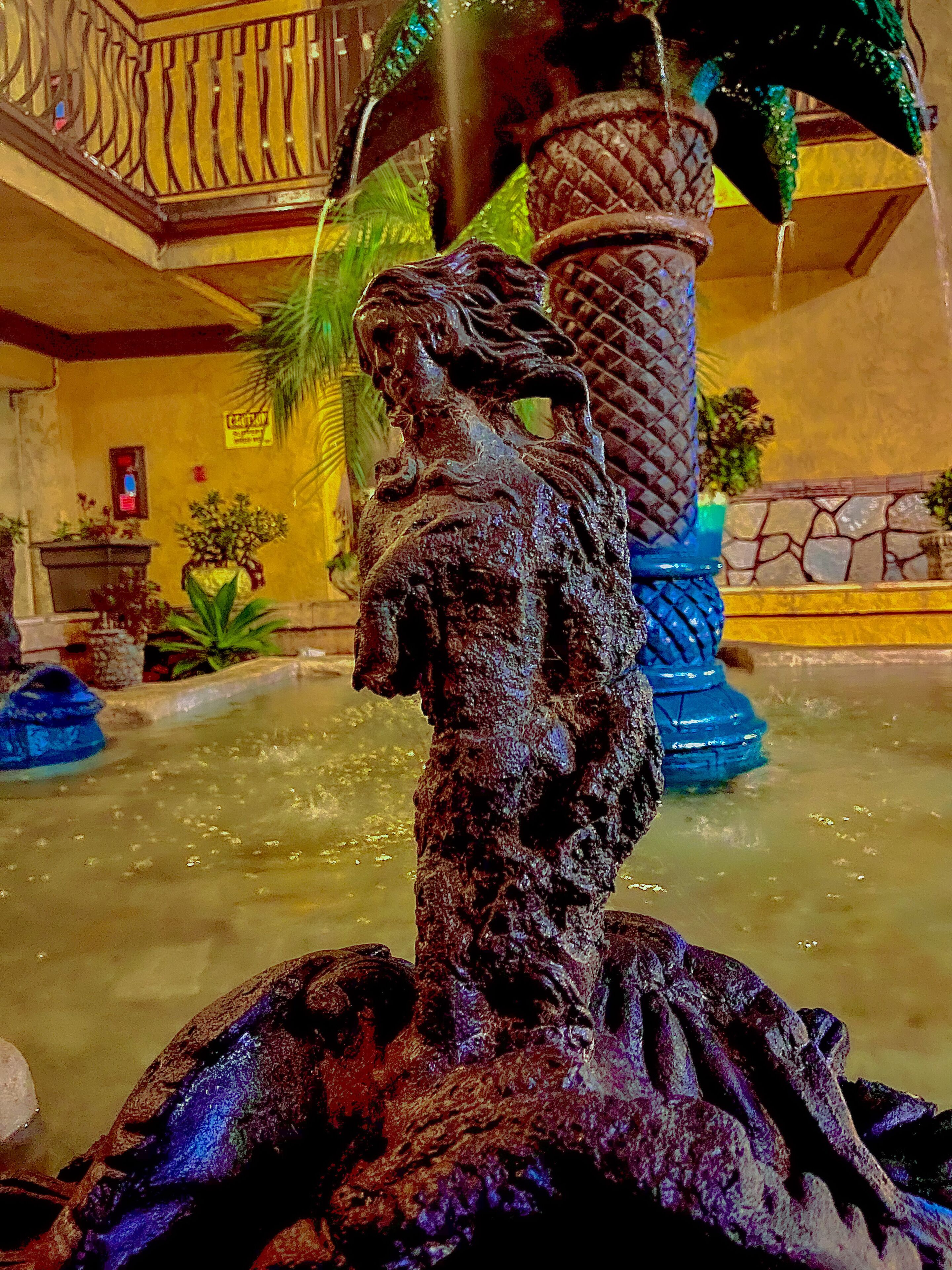 A fountain with a statue of a woman, surrounded by decorative elements and plants.