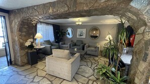 A living room with stone walls, a sofa, armchairs, a coffee table, and potted plants. - Hotel Baja San Diego - A Boutique Hotel (San Ysidro)