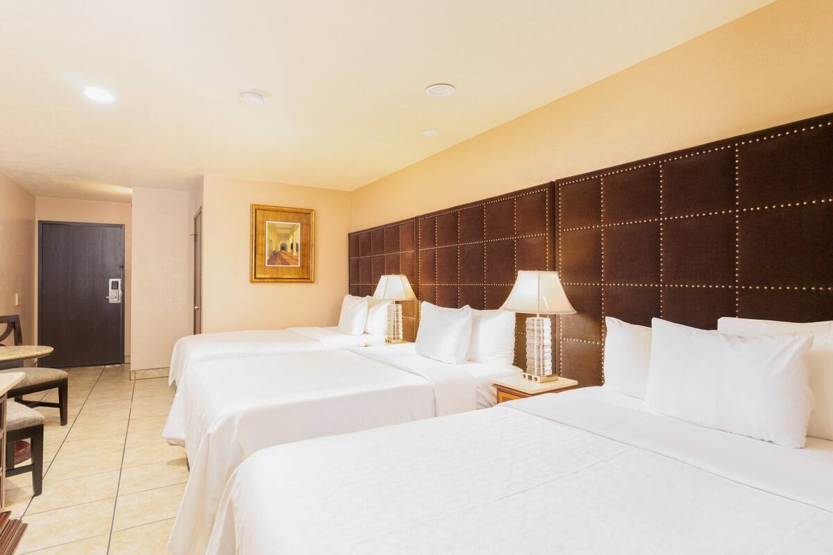 A hotel room with two beds, a desk, and a chair.
