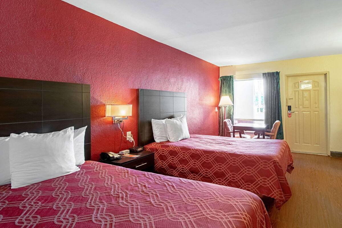 A hotel room with two beds, a desk, and a chair.
