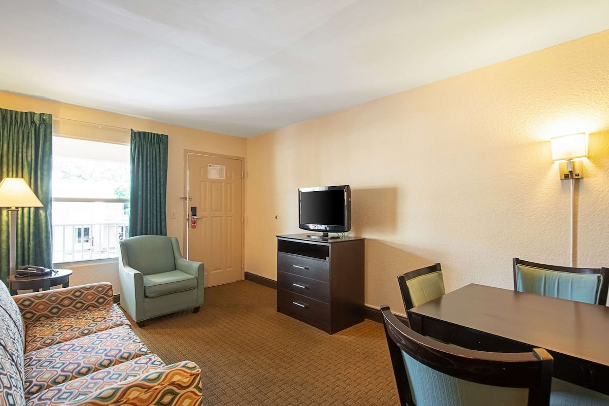 A hotel room with a bed, a desk, a chair, a television, and a window with curtains.