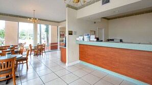 A hotel lobby with a reception desk, wooden chairs, a chandelier, and large windows. - Econo Lodge Inn & Suites Clearwater Central (Clearwater)