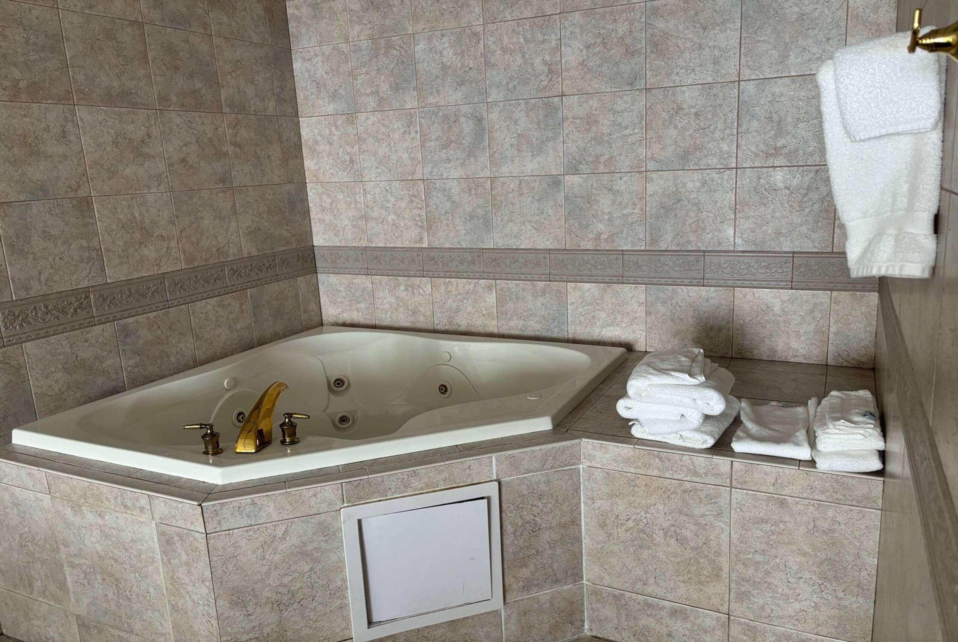 A bathroom with a large bathtub, a towel rack, and neatly folded towels.