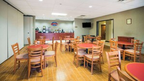 A dining area with multiple tables and chairs, a counter with a beverage station, and a television mounted on the wall. - Baymont by Wyndham Johnson City (Johnson City)
