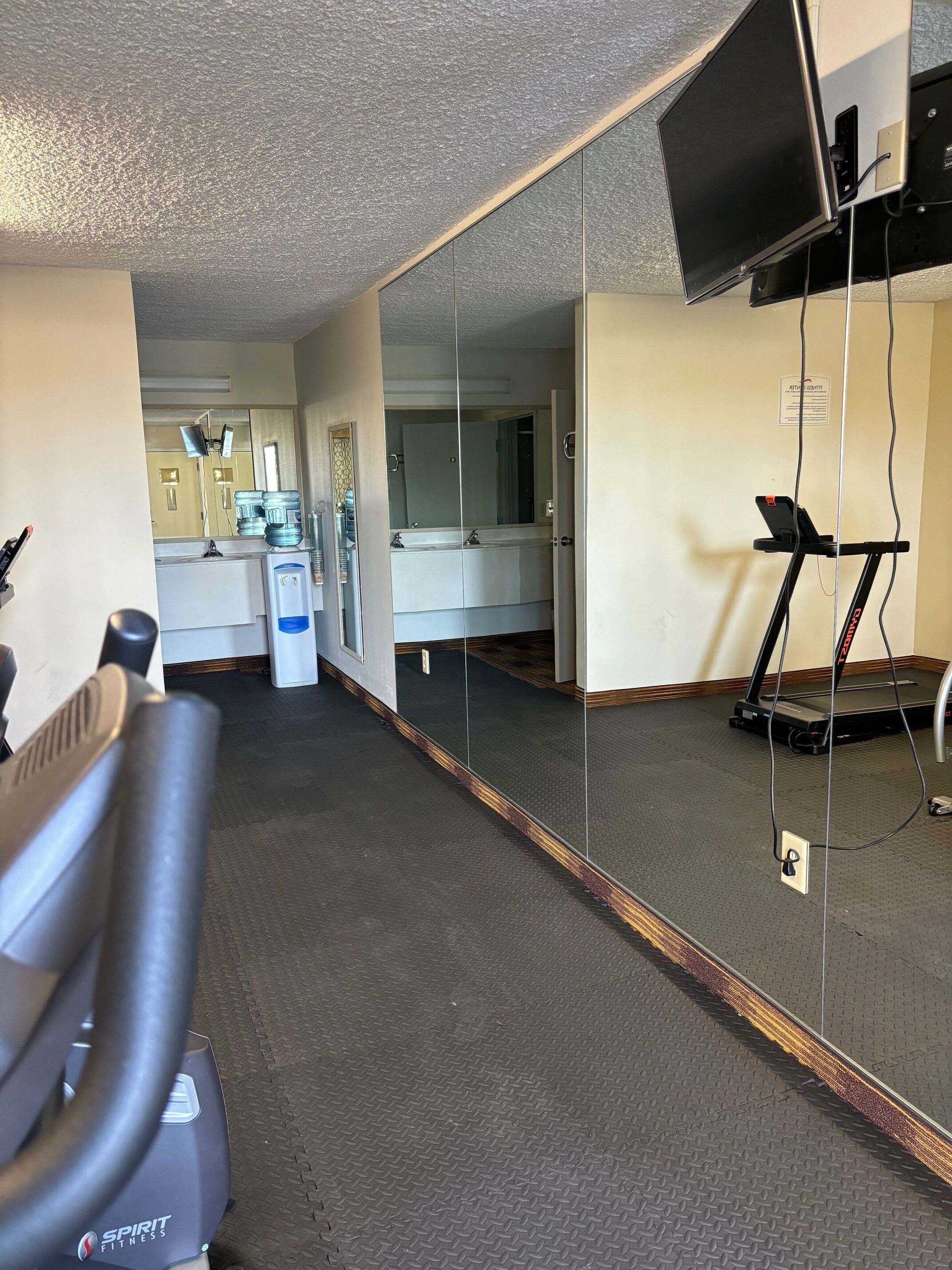 A gym with a treadmill, stationary bike, and water dispenser.