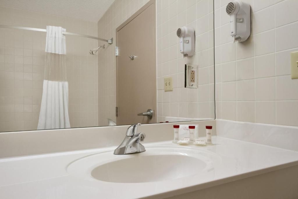 A bathroom with a sink, mirror, towel rack, and a hairdryer mounted on the wall.