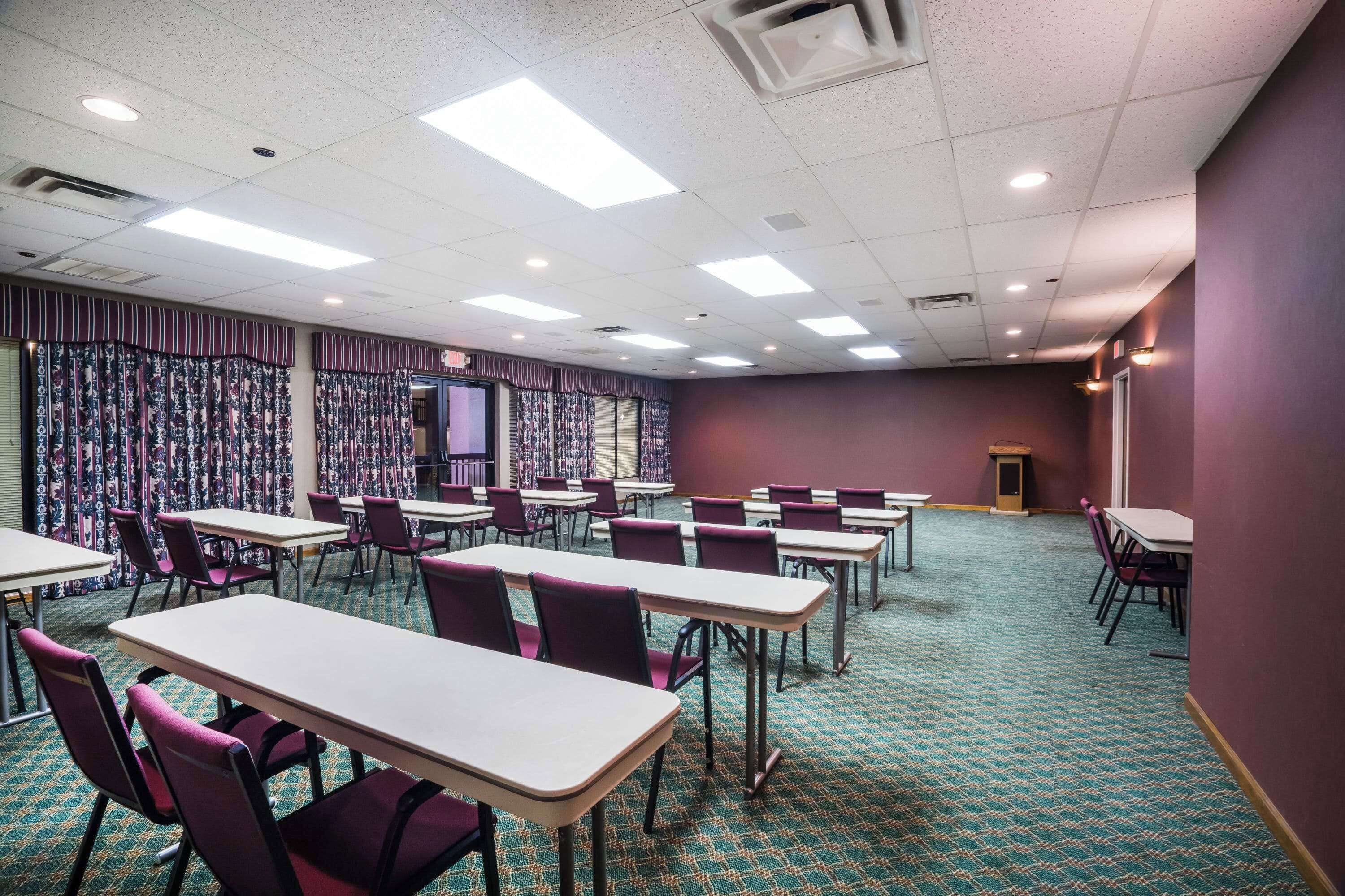 A conference room with tables and chairs, patterned curtains, and a carpeted floor.