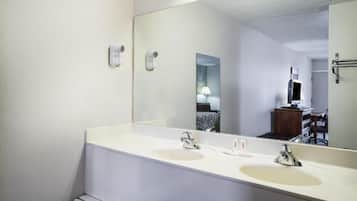 Ein Hotelbadezimmer mit zwei Waschbecken, einem großen Spiegel und einem an der Wand befestigten Föhn.