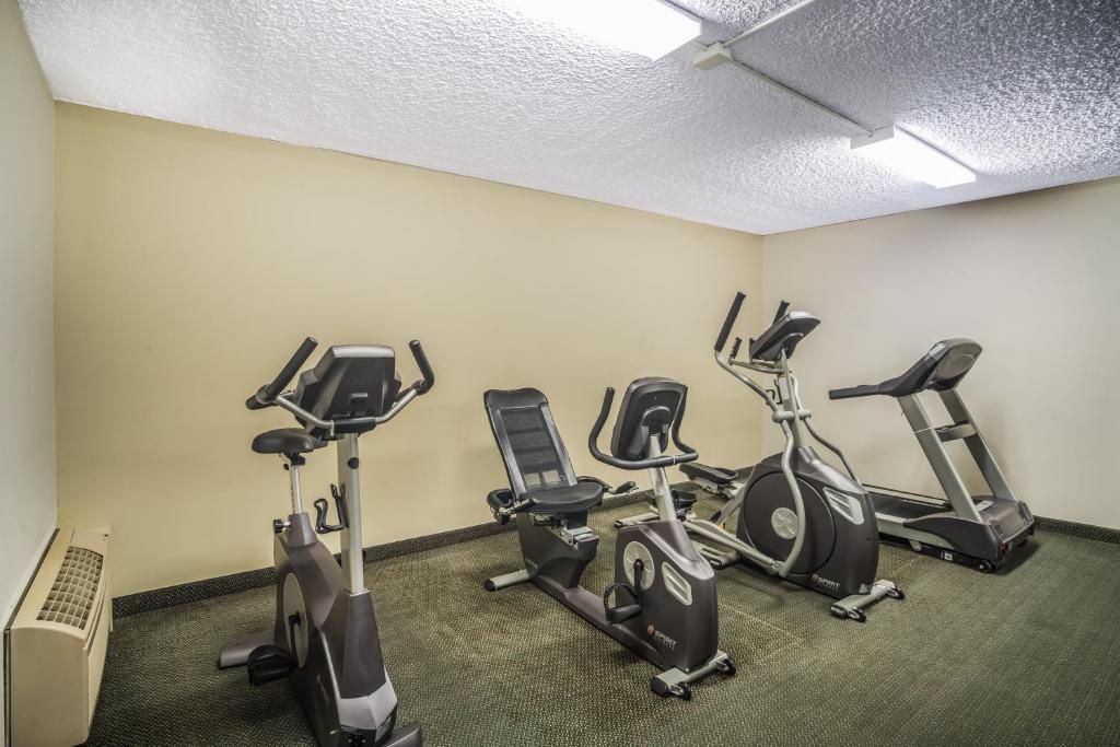 A gym with three stationary bikes and a treadmill.