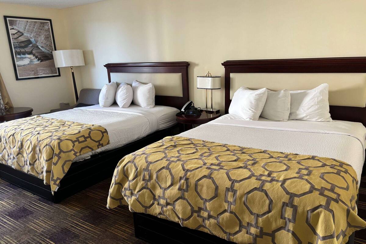 Two double beds with headboards, a bedside table with a lamp, and a framed picture on the wall.