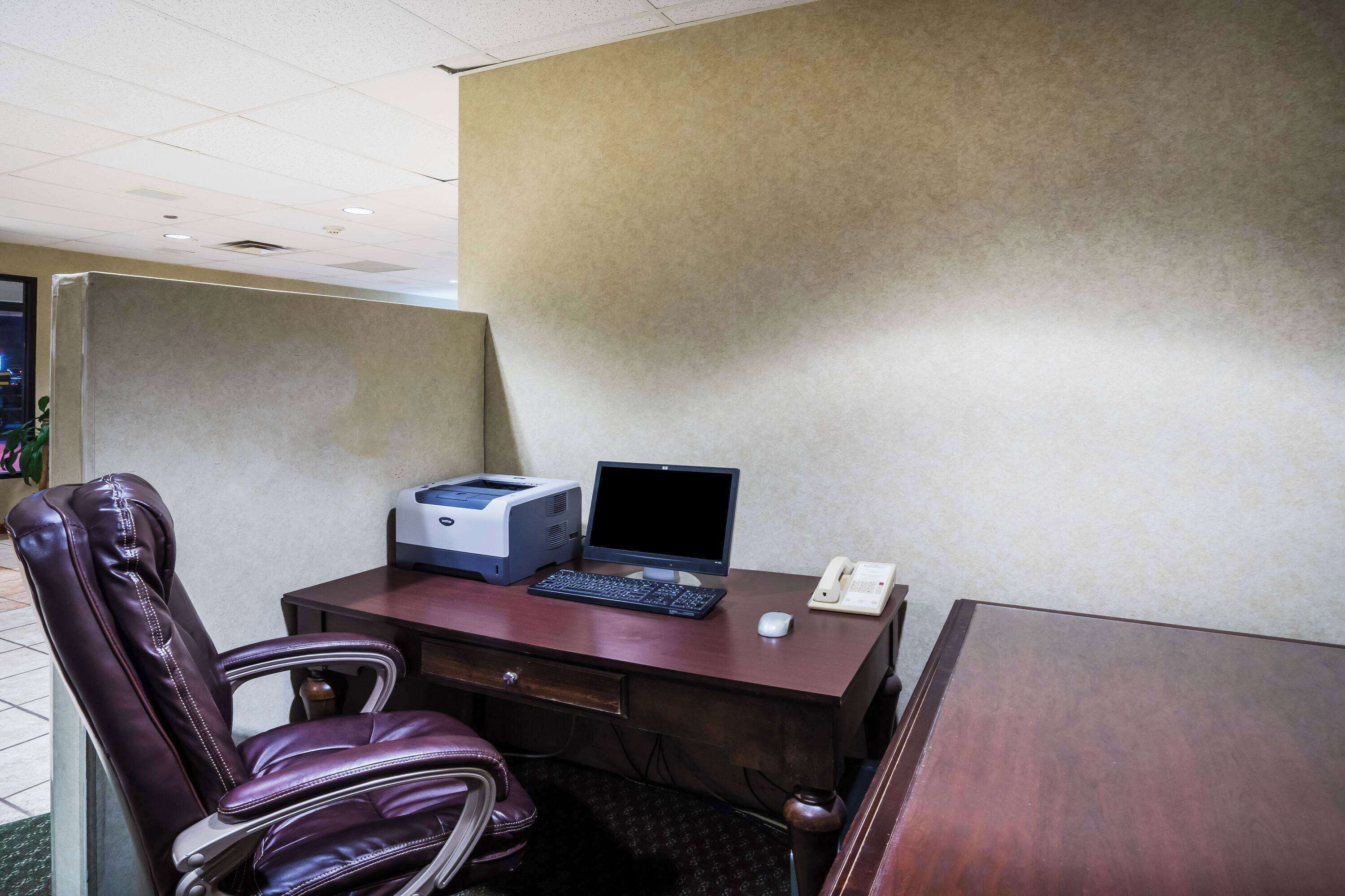 A private office with a desk, computer, printer, telephone, and leather chair.