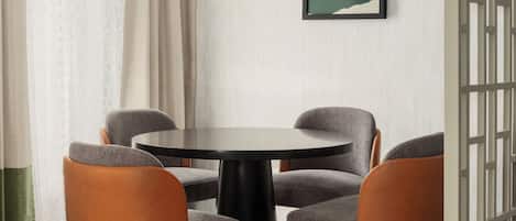A dining area with a round table, four chairs, and a framed picture on the wall.