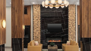 A modern living room with a fireplace, two sofas, a coffee table, and a TV mounted on the wall. - Le Parc Gatineau, Tapestry Collection by Hilton (Gatineau)
