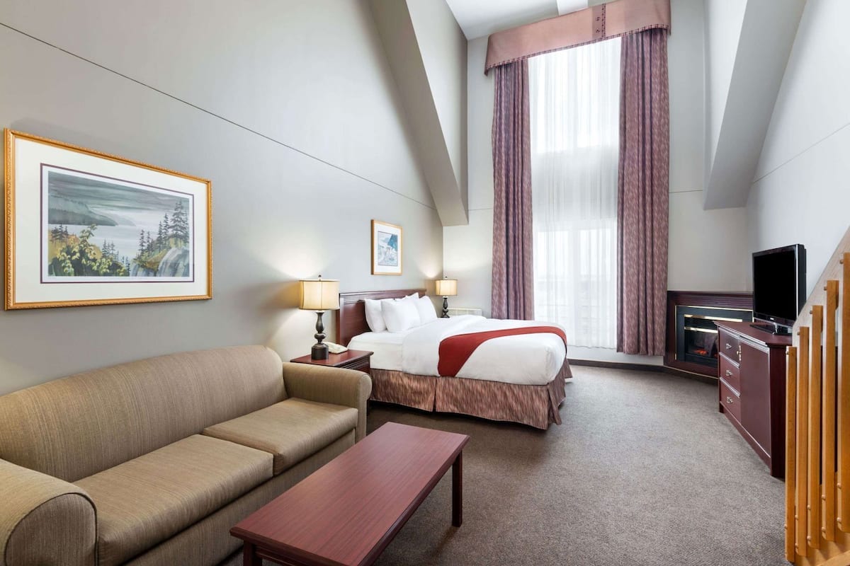 Une chambre d’hôtel avec un lit, un canapé, une télévision et un bureau.