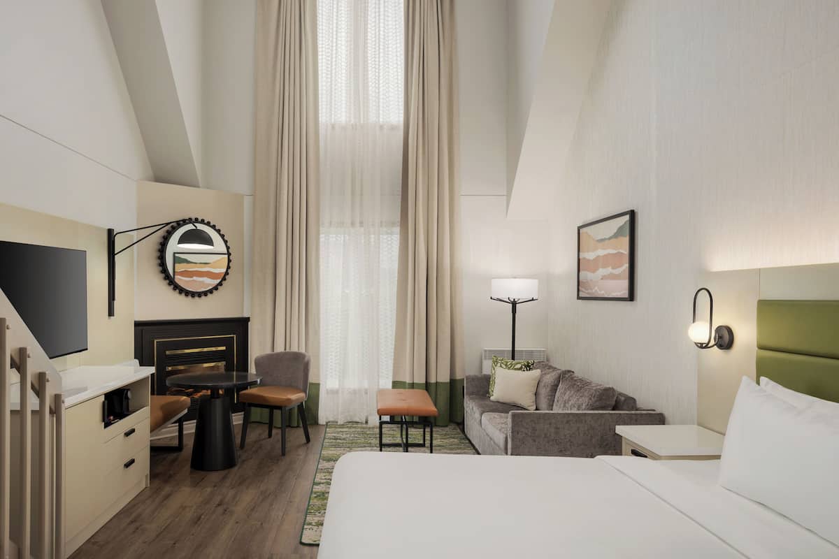 Une chambre d’hôtel équipée d’un lit, d’une télévision, d’un bureau, d’une chaise, d’un canapé, d’une lampe et d’une cheminée.