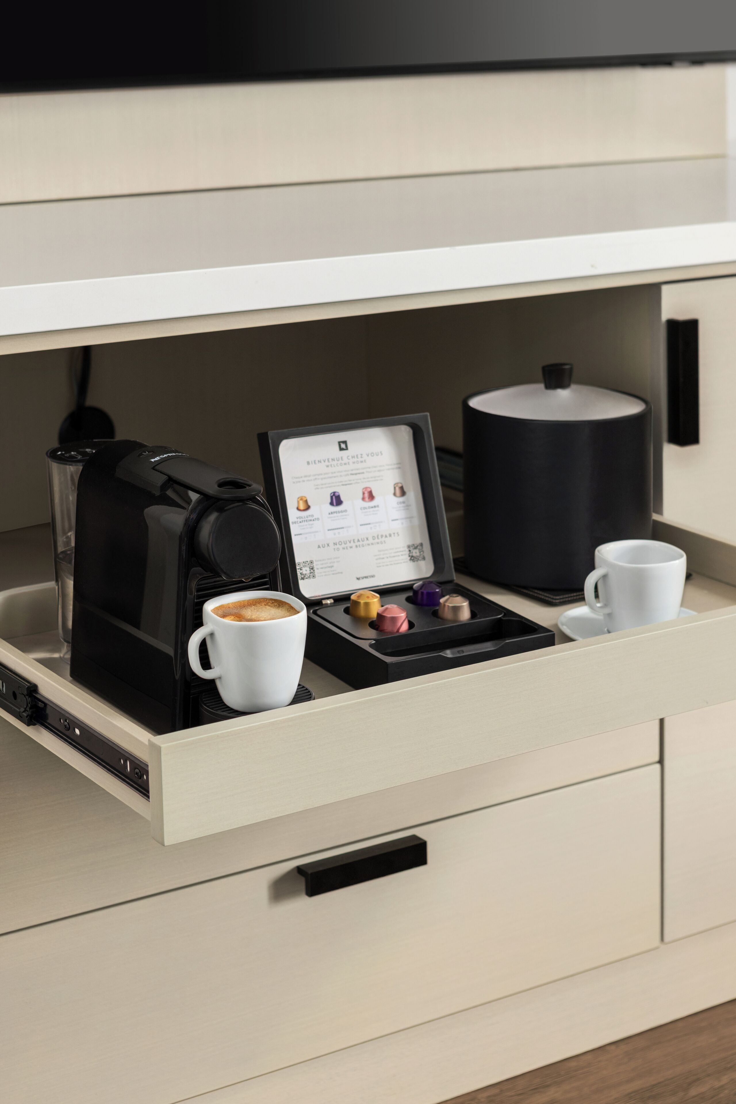 Una cafetera, una taza de café, un menú y una tetera sobre una encimera.