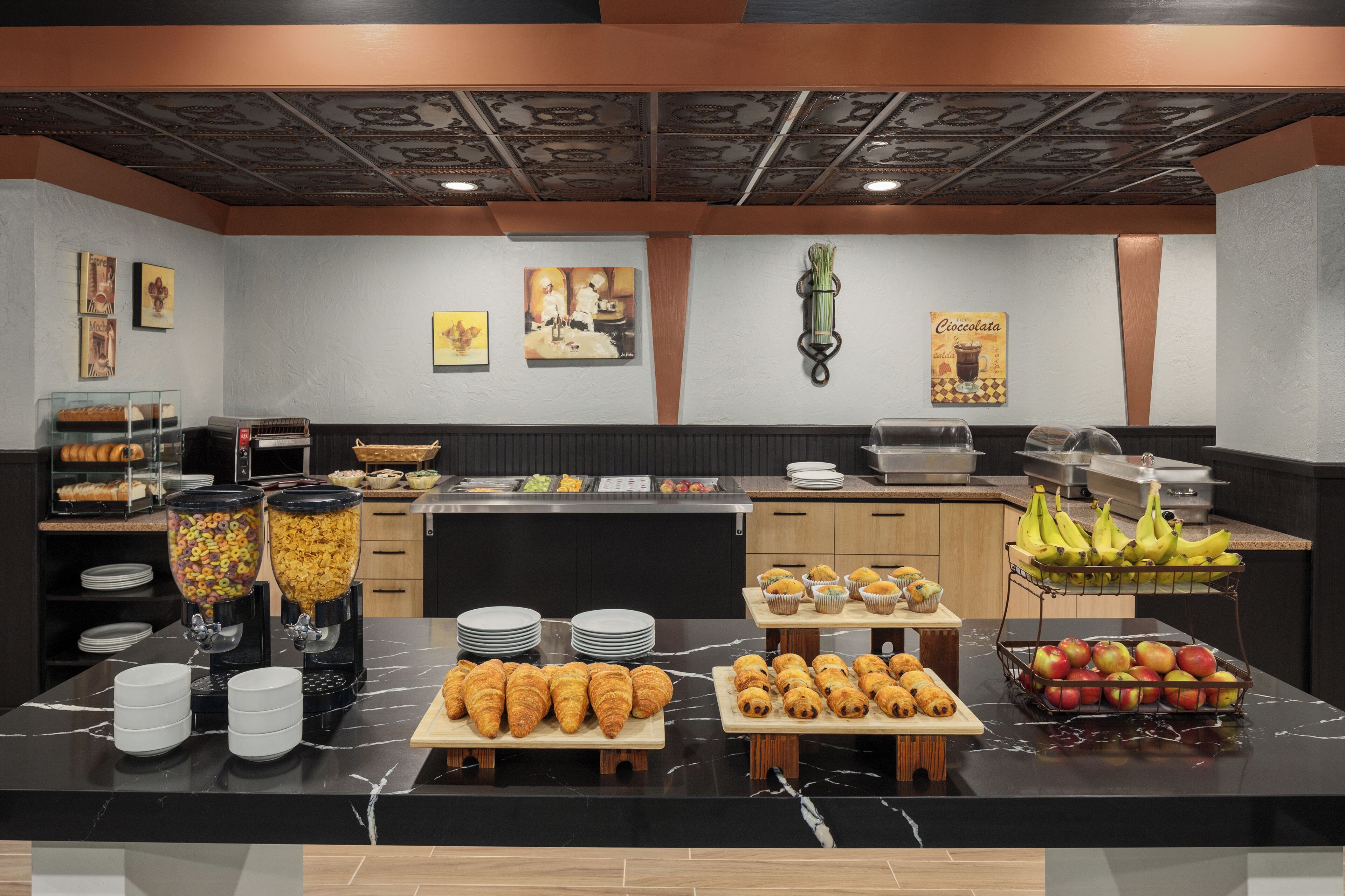A buffet with various food items, a coffee station, and a fruit display.